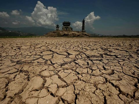 This file photo taken on August 23, 2022 shows caked mud before the usually half submerged Luoxing Dun, a small island with ancient temples on it, in China's largest freshwater Poyang Lake in Juijiang, China's central Jiangxi province.  