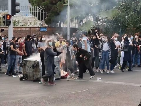 This grab taken from a UGC video and dated to September 22, 2022 shows Iranian demonstrators burning their headscarves and setting fire to a trash bin in the capital Tehran. 
