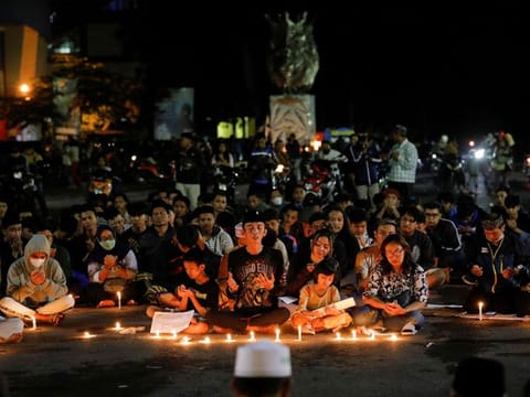  Arema football club supporters pray during a vigil outside the Kanjuruhan stadium to pay condolence to the victims in Malang, October 2, 2022. 