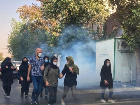 In this Saturday, Oct. 1, 2022, photo taken by an individual and obtained by the AP outside Iran, tear gas is fired by security to disperse protestors in front of the Tehran University, Iran.