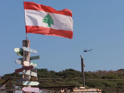 An aircraft flies past as signs bearing names of cities are seen in Naqoura, near the Lebanese-Israeli border, southern Lebanon, October 11, 2022. 