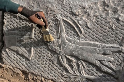 An Iraqi worker excavates a rock-carving relief recently found at the Mashki Gate, one of the monumental gates to the ancient Assyrian city of Nineveh, on the outskirts of what is today the northern Iraqi city of Mosul on October 19, 2022.  