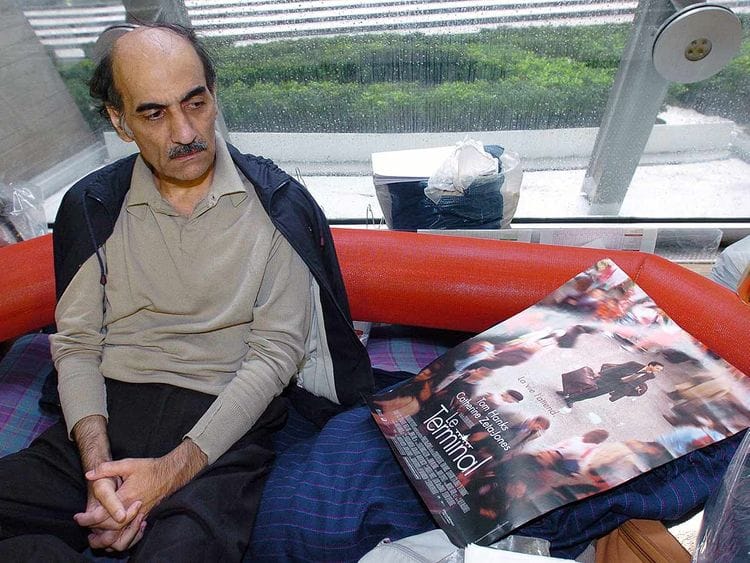In this file photo taken on August 12, 2004 Mehran Karimi Nasseri looks at a poster of the movie inspired by his life, in the terminal 1 of Paris Charles De Gaulle airport.