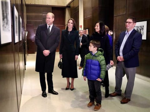 Boston Mayor Michelle Wu, right, and her family show photographs of the Queen Elizabeth II's visit in 1976, during the visit of Britain's Prince William and Kate, Princess of Wales, to Boston City Hall on Wednesday, Nov. 30, 2022, in Boston. The Prince and Princess of Wales are making their first overseas trip since the death of Queen Elizabeth II in September.  (Nancy Lane/The Boston Herald via AP, Pool)