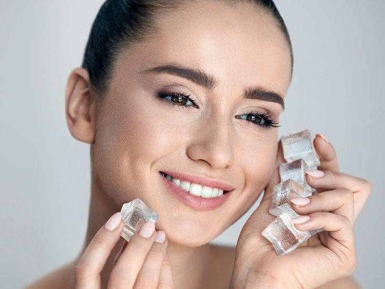 Woman applying ice on her face 