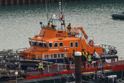 Migrants picked up at sea while attempting to cross the English Channel, are escorted off from the UK Royal National Lifeboat Institution (RNLI) lifeboat at the Marina in Dover, southeast England, on December 14, 2022.
