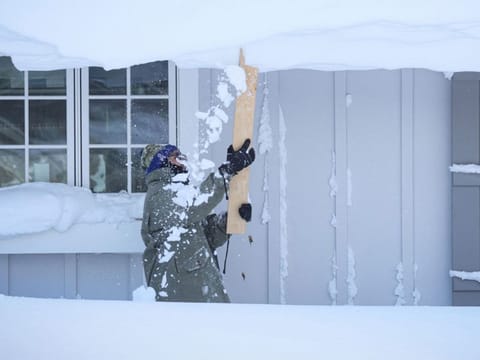 A man clears snow from his roof following a winter storm that hit the Buffalo region in Amherst, New York.