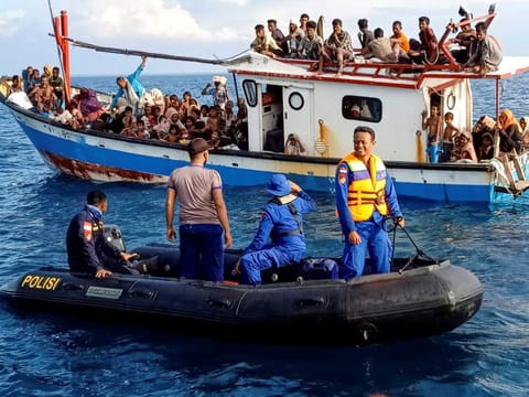 Rohingya refugees rescued by fishermen are seen on a boat behind a patrol boat near the coast of Seunuddon beach in North Aceh, Indonesia, June 24, 2020.