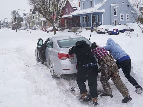 Neighbours help push a motorist stuck in the snow in Buffalo, N.Y