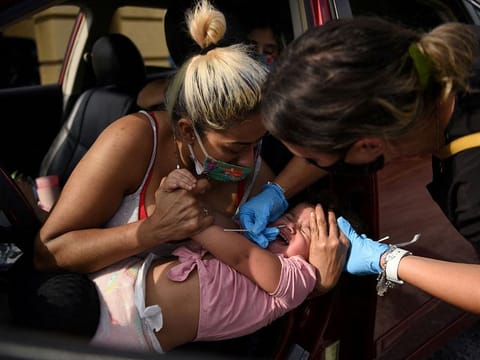 A healthcare worker tests a child for the coronavirus at a drive-through testing site as the Omicron variant continues to spread through the country in Houston, Texas.