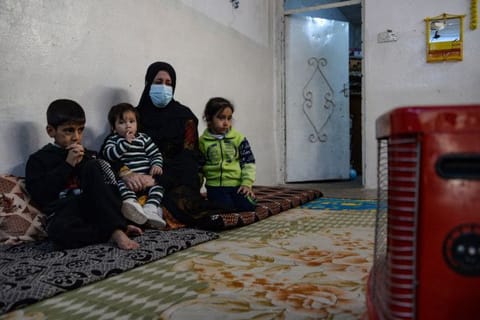 Alia Abdel-Razak,  a woman deprived of crucial civil status documents, is pictured with 3 of her children in her home in Iraq's northern city of Mosul on December 11, 2022.  Many in Mosul struggle with endless red tape, but also the fallout from the gruelling battle to defeat the Islamic State group, to obtain documents like marriage and birth certificates.