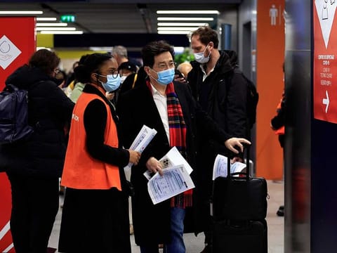 Passengers arriving from China wait in front of a COVID-19 testing area set at the Roissy Charles de Gaulle airport, north of Paris, Sunday, Jan. 1, 2023. 