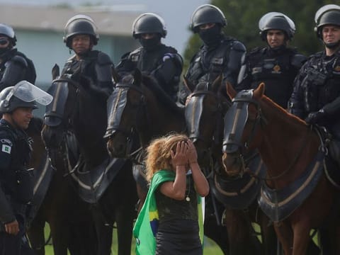 A demonstrator reacts next to security forces as supporters of Brazil's former President Jair Bolsonaro leave a camp in front of the the Army Headquarters in Brasilia, Brazil, January 9, 2023. 