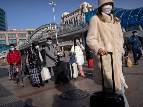 Travellers walk toward the entrance to the Beijing Railway Station on January 14, 2023. Millions of Chinese are expected to travel during the Lunar New Year holiday period this year. 