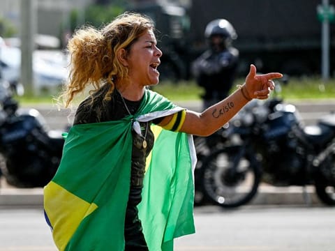 A supporter of Brazil's far-right ex-president Jair Bolsonaro gestures as soldiers dismantle a camp set up by protesters in Brasilia on January 9, 2023, a day after former president’s backers invaded the Congress, presidential palace and Supreme Court. 