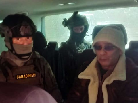 This handout picture released on January 16, 2023 by the Ufficio Stampa Comando Generale Carabinieri shows Italy's top wanted mafia boss, Matteo Messina Denaro (R), being escorted in a vehicle by carabinieri after he was arrested in his native Sicily after 30 years on the run. 