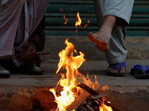 Labourers keep themselves warm near a fire during a cold morning, as they wait for work at the market in Karachi, Pakistan January 13, 2023. Reuters