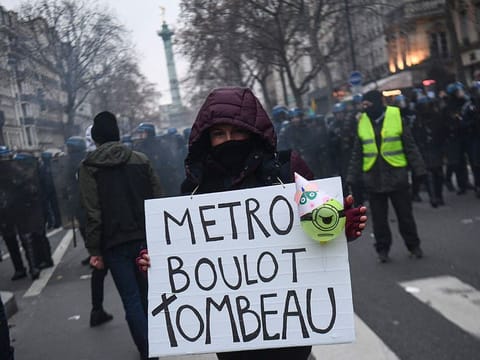 A demonstrator holds a sign reading 'Metro, job, tomb'  during a rally called by French trade unions in Paris on January 19, 2023. 