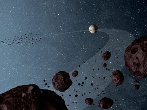 New results from NASA's Wide-field Infrared Explorer, or WISE, reveal that the Jovian Trojans - asteroids that lap the sun in the same orbit as Jupiter - are uniformly dark with a hint of burgundy, and have matte surfaces that reflect little sunlight. The results are illustrated in this artist's concept, showing both the leading and trailing packs of Trojans in orbit with Jupiter.  