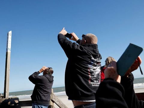 People photograph a suspected Chinese spy balloon as it floats off the coast in Surfside Beach, South Carolina, US, February 4, 2023. 