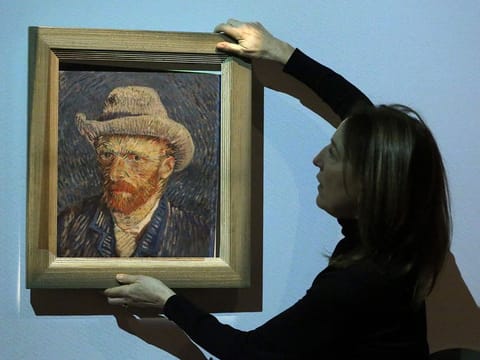 Emilie Gordenker, director of the Van Gogh Museum, removes the frame of a reproduction of the painting "Self-Portrait with Grey Felt Hat" by Vincent Van Gogh as part of an interactive section of the exhibition "Choosing Vincent - Portrait of a family history" at Van Gogh Museum in Amsterdam, on February 8, 2023. 