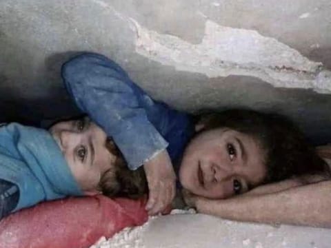  A photo of a seven-year-old girl shielding her younger brother under the quake rubble has gone viral 