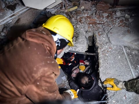 Emergency workers and medics rescue a woman out of the debris of a collapsed building in Elbistan, Kahramanmaras, in southern Turkey, on February 7, 2023.  