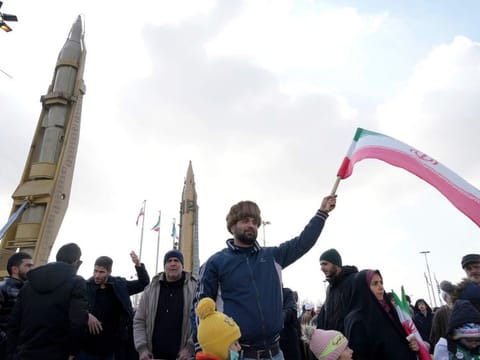 A man waves an Iranian flag as domestically built missiles are displayed at background during the annual rally commemorating Iran's 1979 Islamic Revolution, in Tehran, on Feb. 11, 2023.  
