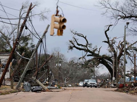 Cars carefully navigate around downed trees and power lines on Chestnut Boulevard in Selma, Alabama, Friday, January 13, 2023, after a tornado passed through the area the day before. 