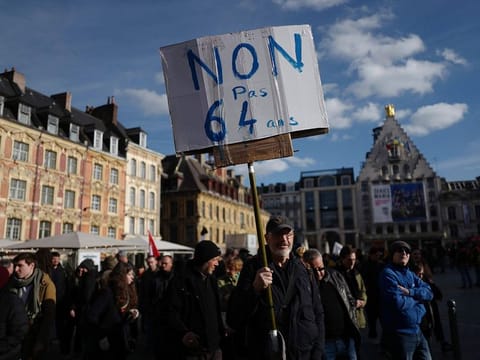 A man holds a poster reading "No, not at 64", during a demonstration in Lille, northern France.