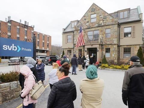 Customers wait in line outside a branch of the Silicon Valley Bank (SVB) in Wellesley, Massachusetts, on March 13, 2023.     