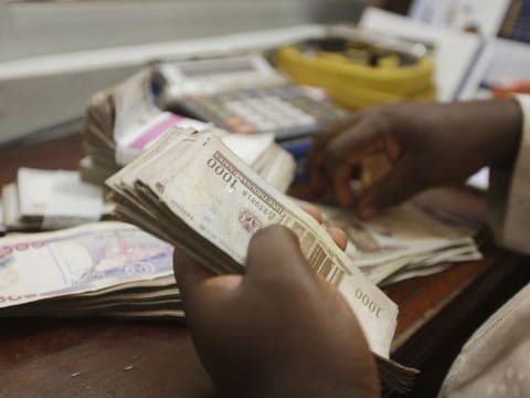 FILE - A money changer counts Nigerian naira currency at a bureau de change, in Lagos Nigeria, Oct. 20, 2015. Nigeria’s central bank has extended the timeline to swap out its old currency for redesigned notes after the change triggered a cash shortage. On Tuesday, March 14, 2023, both old and redesigned notes were still not available for thousands queued at banks in Nigeria’s capital of Abuja. (AP Photo/Sunday Alamba, File)
