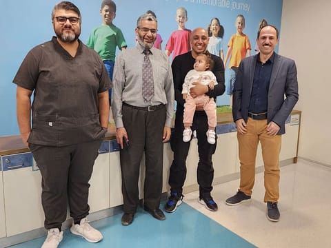 Mariam with her father and a team of doctors after successful treated her life-threatening chest infection