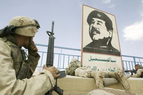 In this file photo dated on April 10, 2003 US marines take position near a portrait of late Iraqi dictator Saddam Hussain in a stadium in Baghdad.  