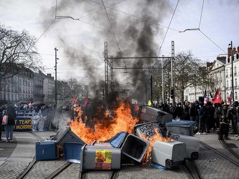 Garbage bins are set on fire by protestors during a demonstration on a 8th day of strikes and protests across the country against the government's proposed pensions overhaul in Nantes on March 15, 2023. 