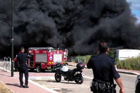 Israeli policemen stand next to smoke from a fire following incoming rockets from Lebanon to Israel in Bezet, northern Israel on April 6, 2023.  