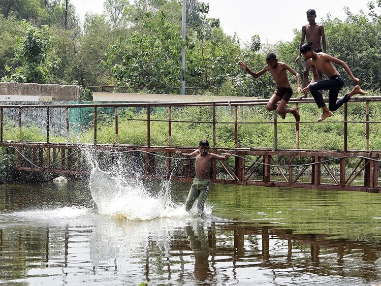Children jump in Kondli canal to beat the scorching heat, in New Delhi on Saturday. 