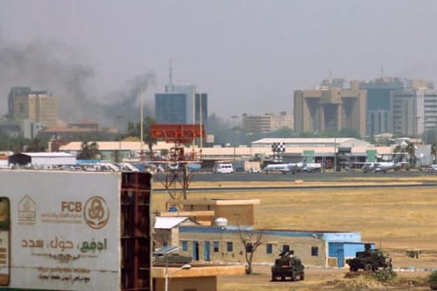 Military vehicles can be seen as smoke bellows above buildings in the vicinity of the Khartoum airport on April 15, 2023, amid clashes in the city.  