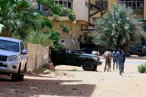 People walk past a military vehicle in Khartoum on April 15, amid reported clashes in the city.  