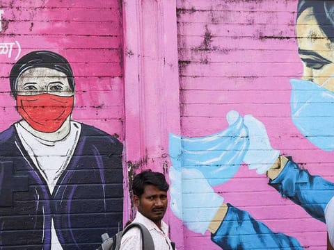 A man walks past a coronavirus (COVID-19) themed mural on a street in Mumbai, India, March 28, 2023. 