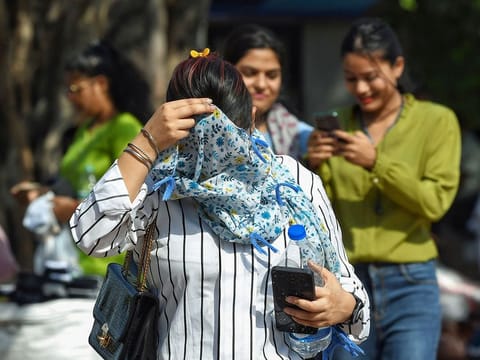 A woman covers her face with a scarf to protect herself from the sun on a hot summer day, in New Delhi.
