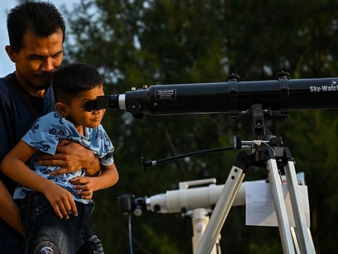 A boy uses a telescope to sight the new moon ahead of Eid al-Fitr which marks the end of the Islamic holy fasting month of Ramadan, on Lhoknga beach in Aceh province, Indonesia on April 20, 2023. 