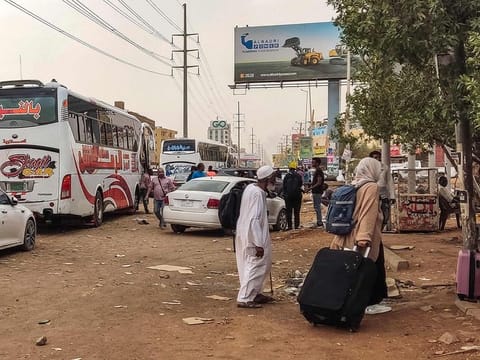 People prepare to board a bus departing from Khartoum in the Sudanese capital's south on April 24, 2023, as battles rage in the city between the army and paramilitaries. 