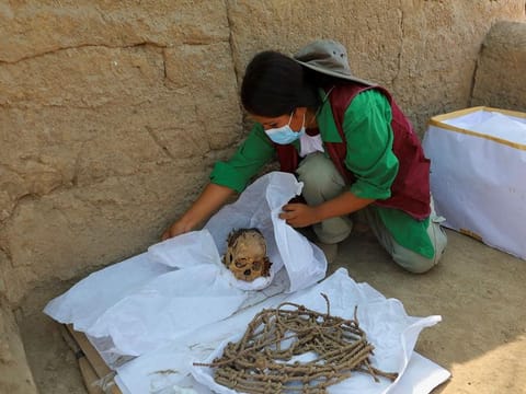 A worker wraps skeletal remains and parts of the funerary bundle of a mummy found by Peruvian archaeologists in the ruins of Cajarmarquilla, in the outskirts of Lima. 