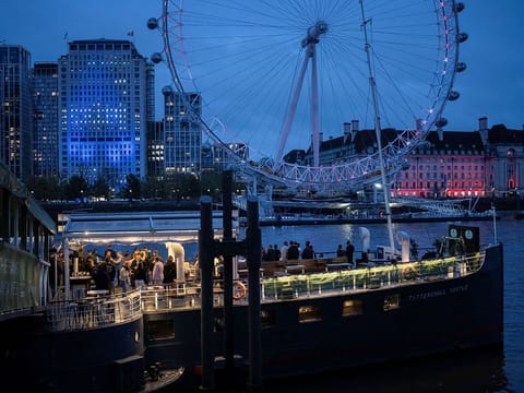 People stand on a floating pub called Tattershall Castle while the London Eye is seen in the background following Britain's King Charles and Queen Camilla's coronation ceremony, in London.