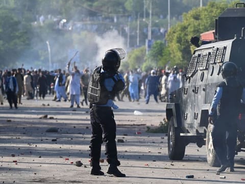 A policeman fires a teargas shell towards Pakistan Tehreek-e-Insaf (PTI) party activists of Khan during a protest outside the police headquarters where Khan is in custody, in Islamabad on May 10, 2023.  