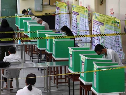 People stand in voting booths as they vote in the general election at a polling station in Bangkok, Thailand, May 14, 2023. 