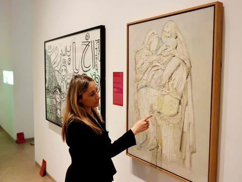 Director Karina Al Helou points at a restored painting titled 'Consolation' (1970) by Lebanese painter Paul Guiragossian, at Sursock Museum in Beirut on May 24, 2023 prior to the reopening ceremony following nearly three years of repairs to its building and collections, which were devastated by the massive August 4 port explosion.  