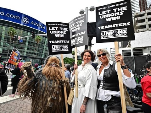 Demonstrators hold signs while picketing during the continuing strike by the Writers Guild of America in Los Angeles, California, on May 26, 2023. 