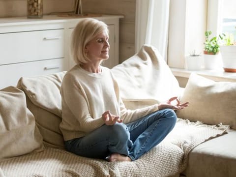 Mindful healthy mature woman practicing meditation at home.